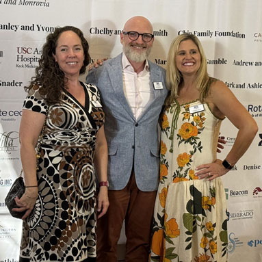 Quinn Bebb, Mark Waterson, and Kim Acosta standing in front of the Sponsorship banner