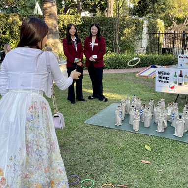 An guest tries her luck at one of the three games available. She's tossing a ring hoping to win a bottle of wine.